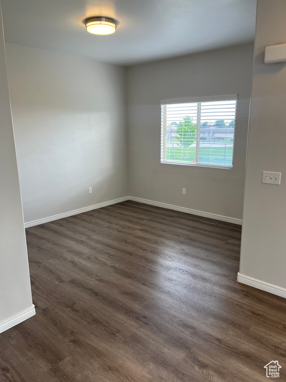 Empty room featuring dark wood finished floors and baseboards