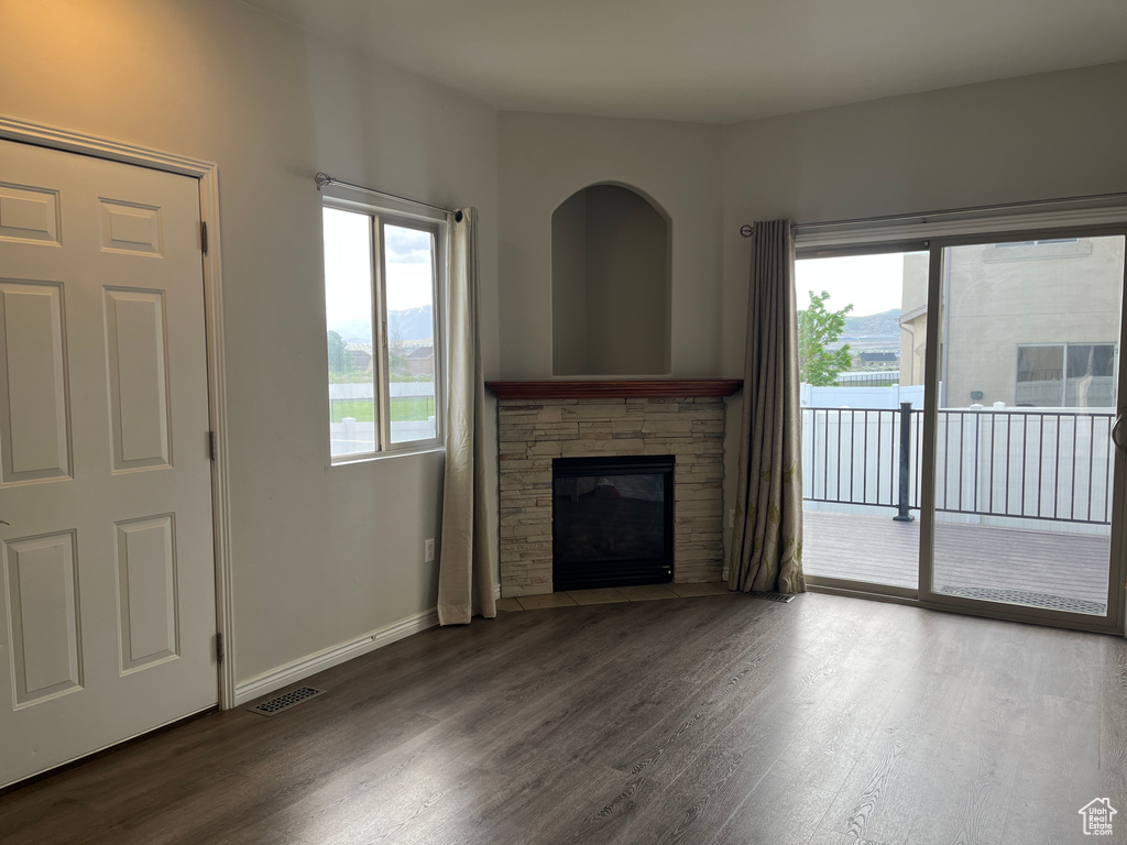Unfurnished living room with wood finished floors, a fireplace, and baseboards