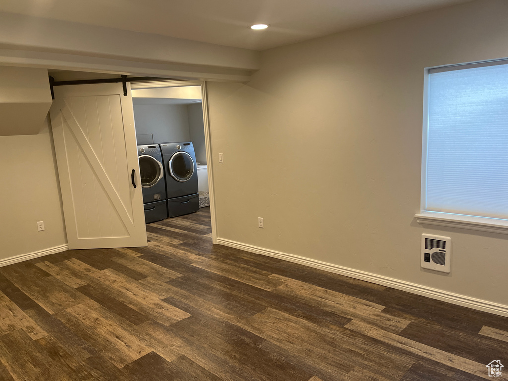 Laundry room with separate washer and dryer, a barn door, heating unit, dark wood-type flooring, and baseboards