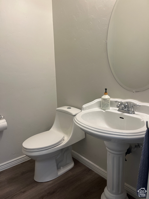 Bathroom with wood finished floors, toilet, baseboards, and a sink