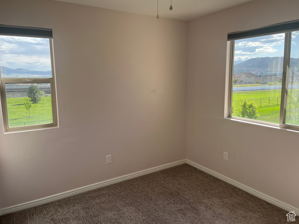 Empty room featuring a mountain view, carpet floors, and baseboards