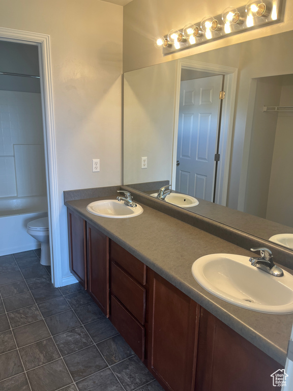 Bathroom featuring double vanity, toilet, and stone finish flooring