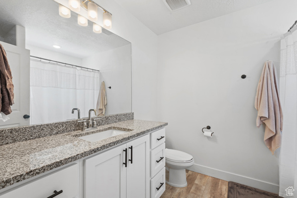 Full bath with vanity, wood finished floors, toilet, and baseboards