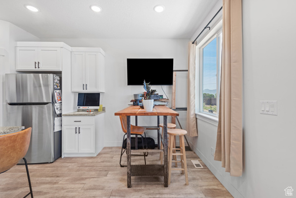 Kitchen with freestanding refrigerator, light wood-style floors, recessed lighting, white cabinets, and plenty of natural light