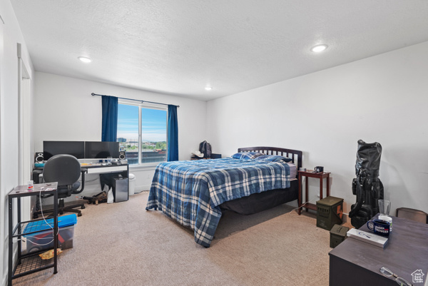 Carpeted bedroom with an office area and recessed lighting
