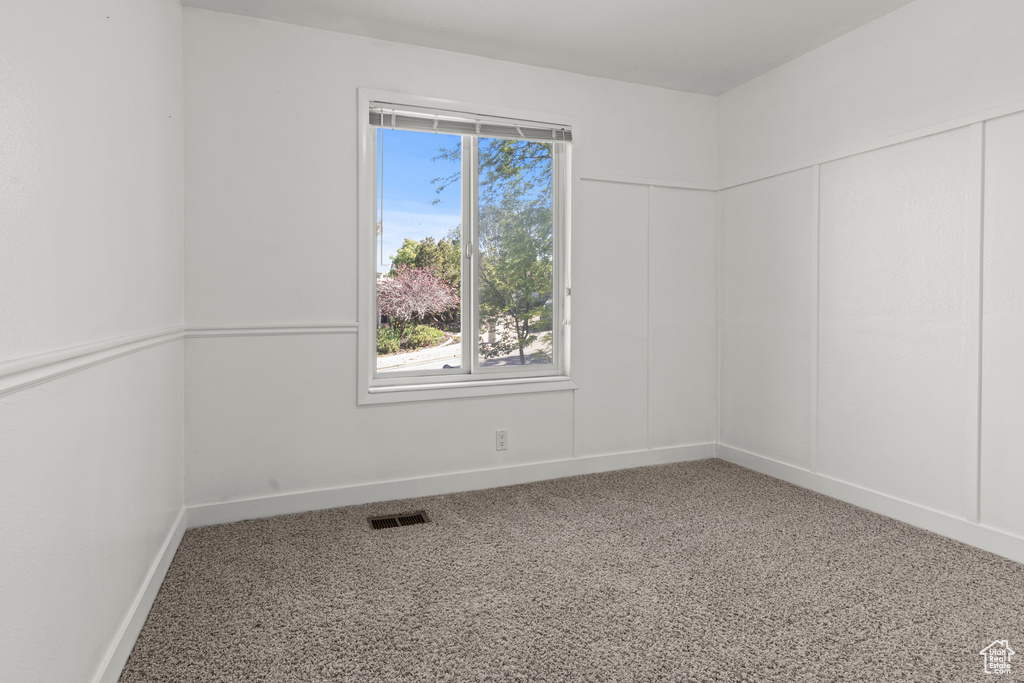Spare room featuring carpet flooring, plenty of natural light, and baseboards