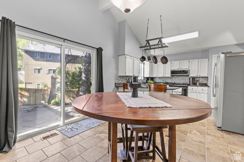 Dining space featuring high vaulted ceiling and light stone finish flooring