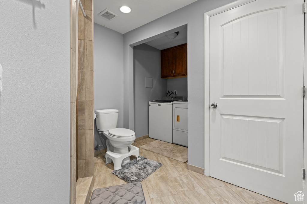 Bathroom with washing machine and clothes dryer, toilet, wood finished floors, a tile shower, and vanity