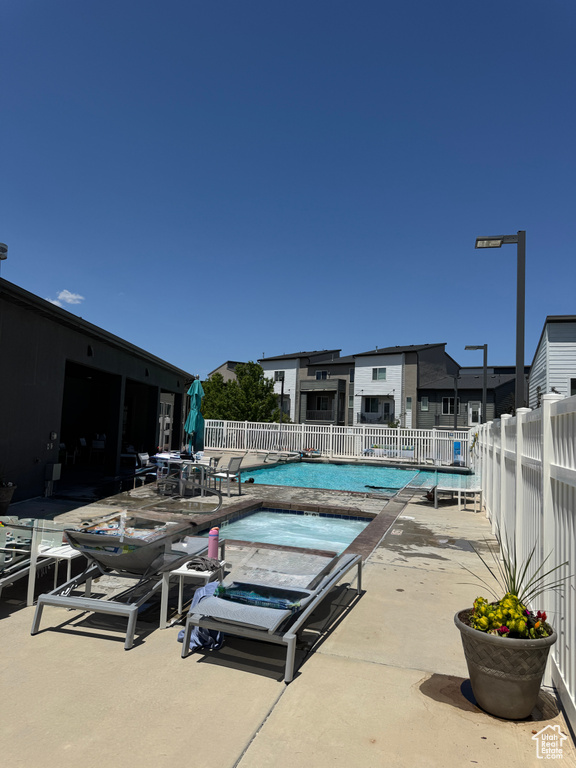 Community pool featuring a patio, a hot tub, and outdoor dining space