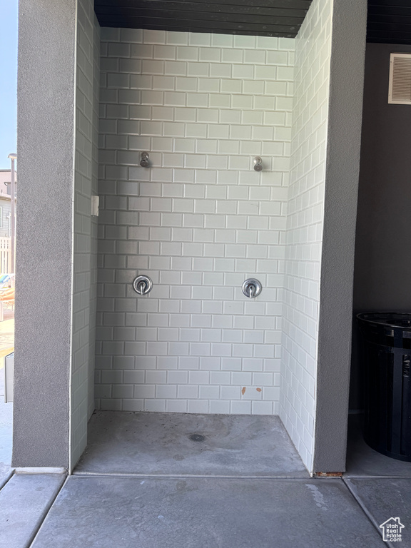 Bathroom featuring a tile shower and concrete floors