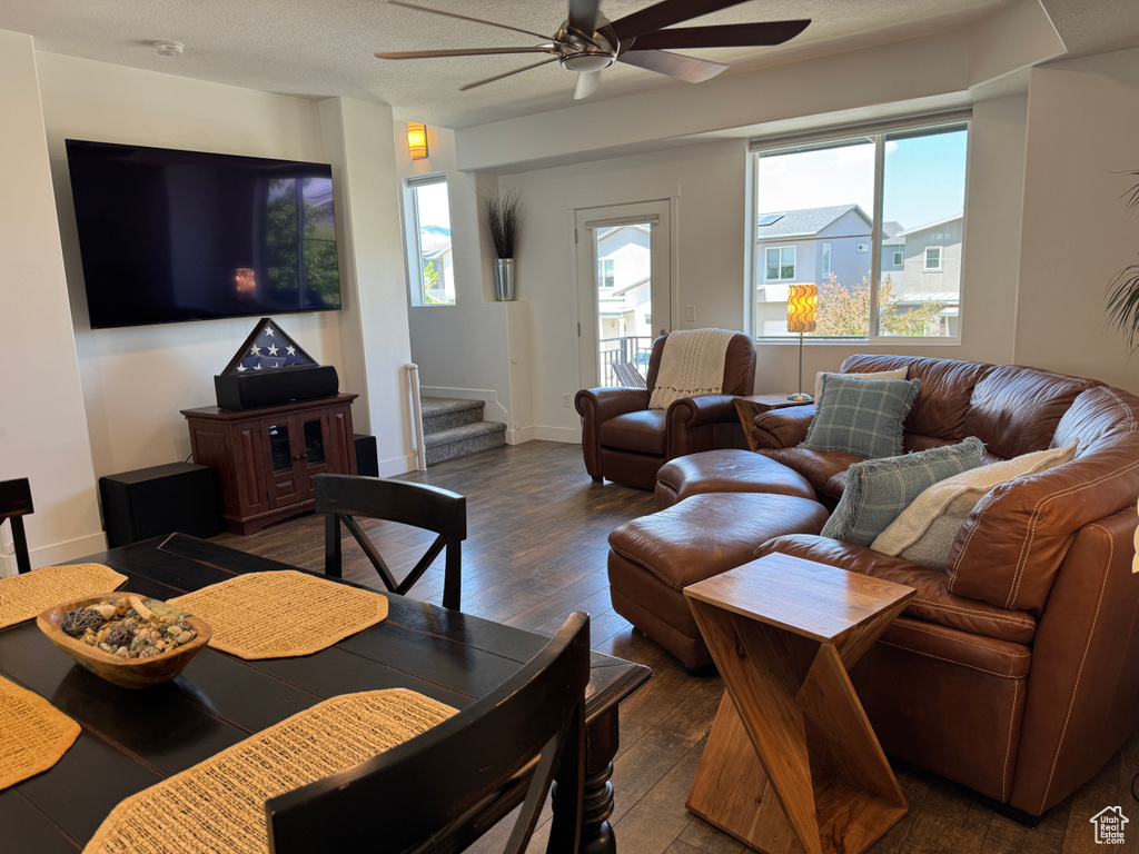 Living area with ceiling fan, hardwood / wood-style floors, stairs, and baseboards