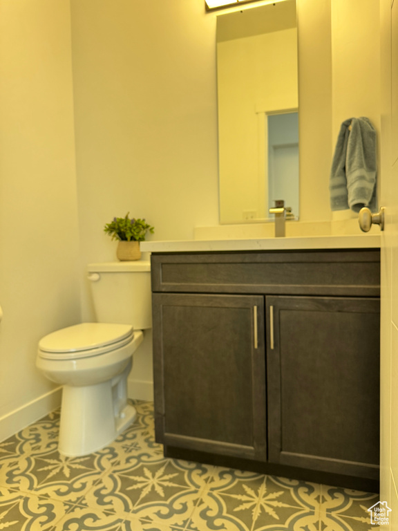 Bathroom with baseboards, toilet, vanity, and tile patterned flooring