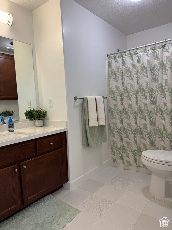 Full bathroom with vanity, toilet, a shower with shower curtain, and a textured ceiling