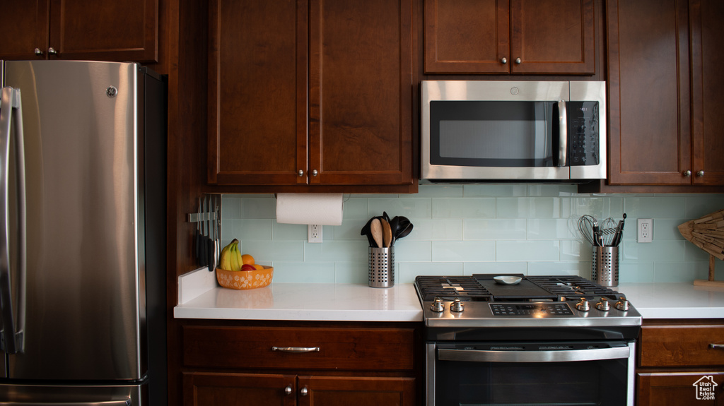 Kitchen with appliances with stainless steel finishes, light countertops, backsplash, and dark brown cabinets