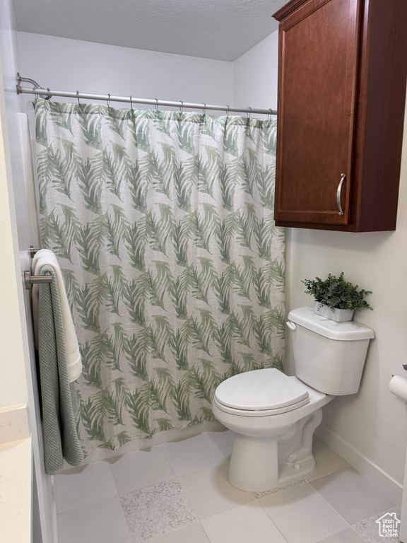 Full bath featuring toilet, a shower with shower curtain, and baseboards