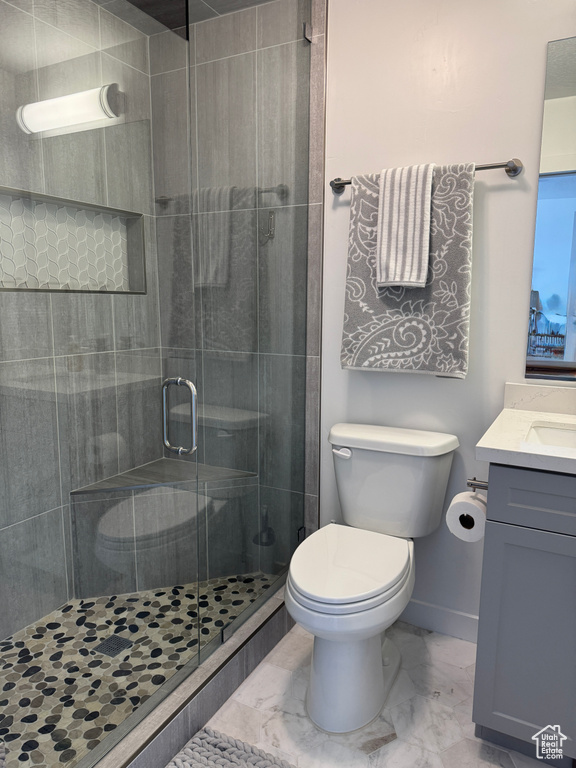 Full bathroom with marble finish floors, vanity, toilet, a shower stall, and baseboards