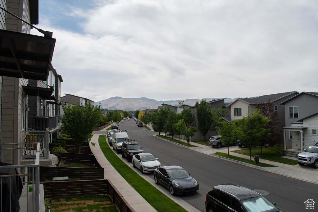 View of asphalt street with sidewalks, a mountain view, curbs, and a residential view