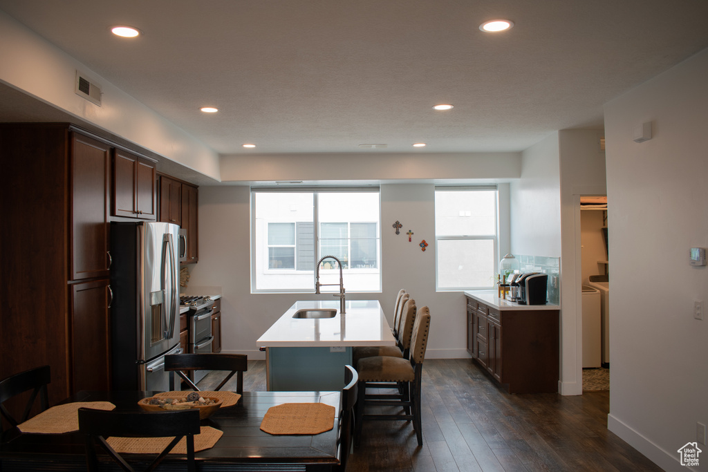 Kitchen with appliances with stainless steel finishes, light countertops, recessed lighting, a center island with sink, and dark wood-style flooring