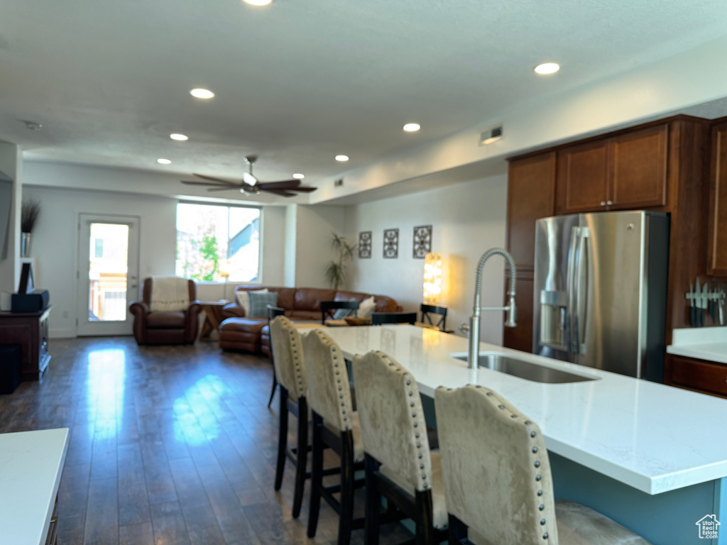 Kitchen with stainless steel refrigerator with ice dispenser, a sink, open floor plan, dark wood-style floors, and recessed lighting