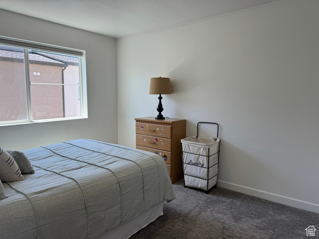 Bedroom with dark carpet and baseboards