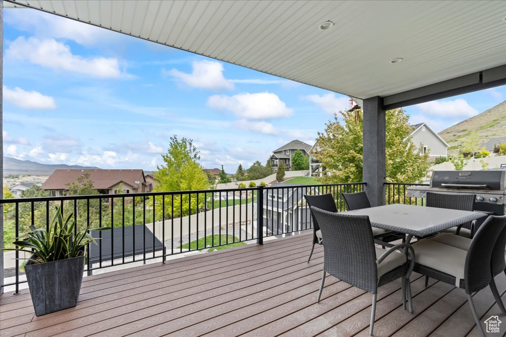 Deck with grilling area, outdoor dining space, a residential view, and a mountain view