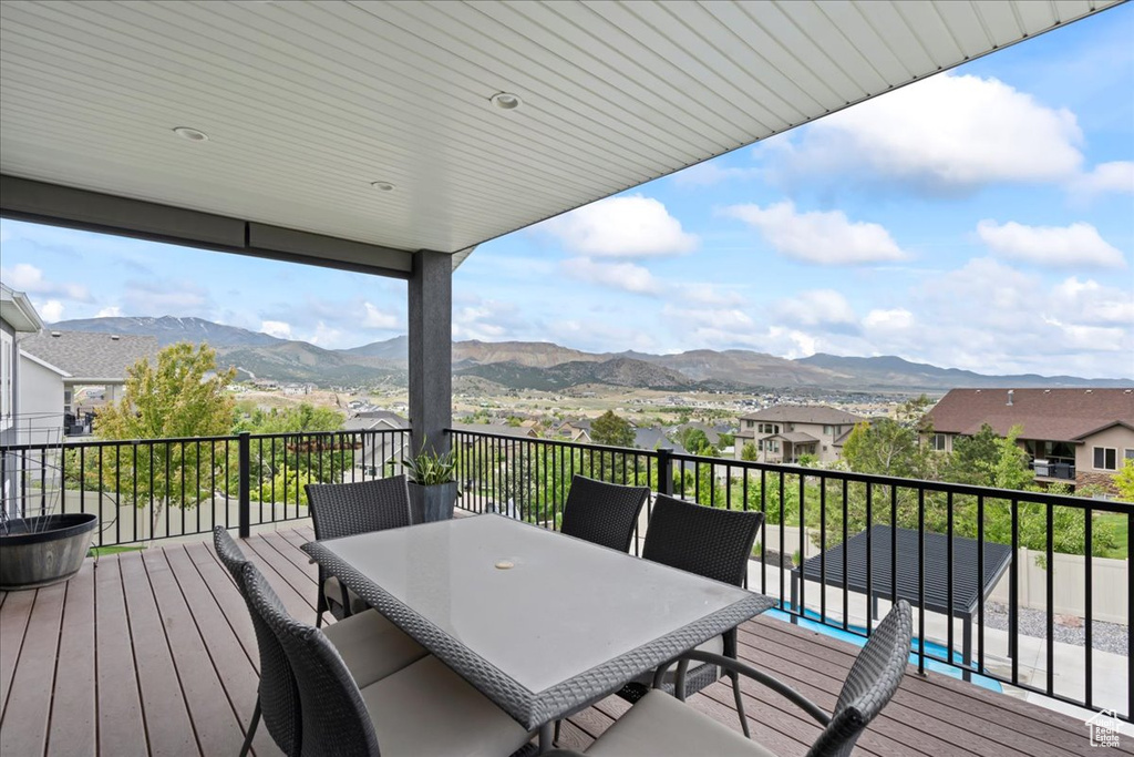 Deck featuring a mountain view, outdoor dining space, and a residential view