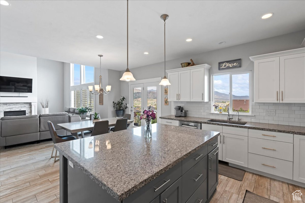 Kitchen featuring a sink, backsplash, open floor plan, white cabinets, and recessed lighting