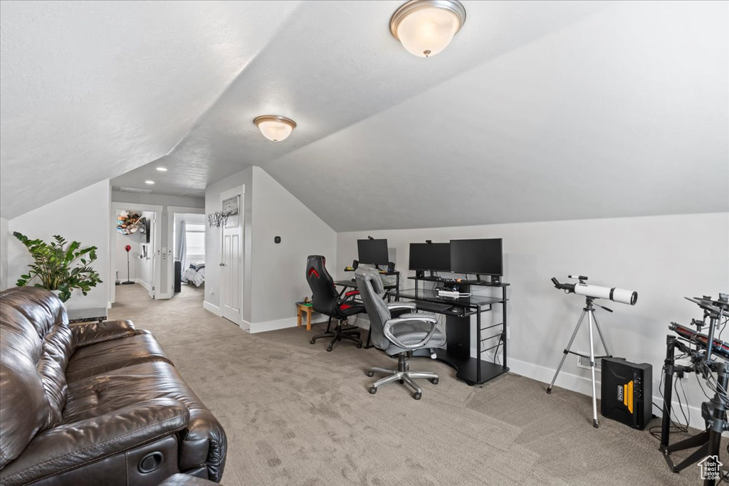 Office area featuring carpet floors, baseboards, and vaulted ceiling