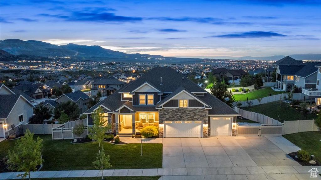 View of front of house featuring stone siding, concrete driveway, a mountain view, a gate, and a residential view