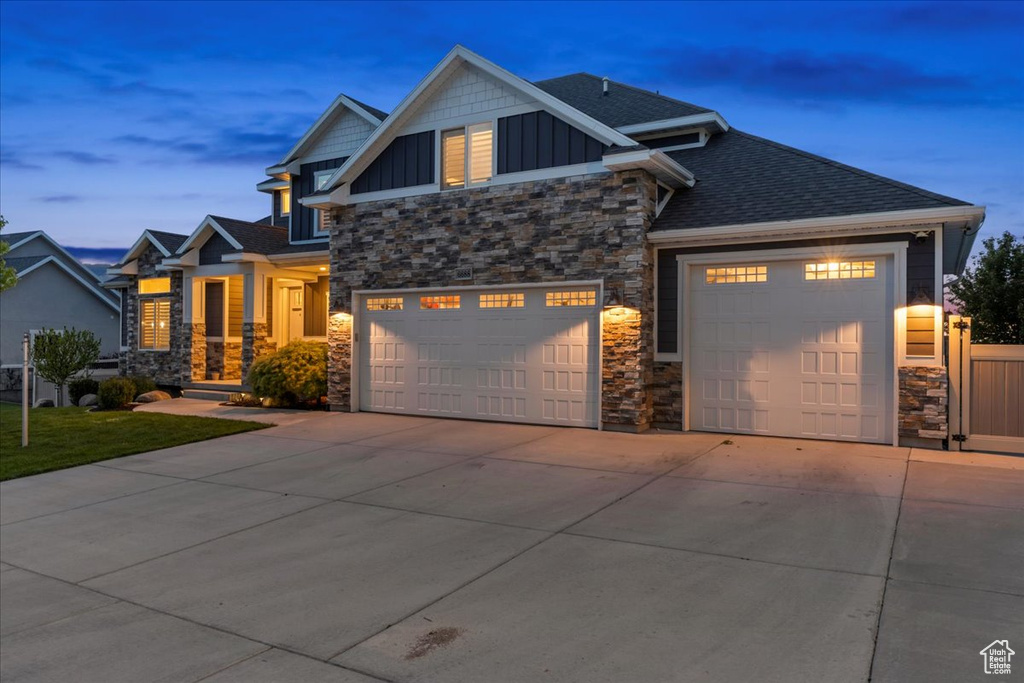 Craftsman inspired home featuring stone siding, board and batten siding, concrete driveway, and roof with shingles