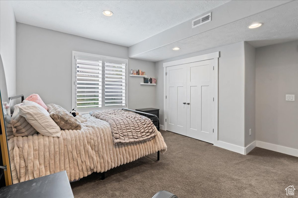 Carpeted bedroom with baseboards, recessed lighting, and a textured ceiling