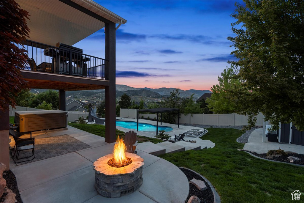 View of patio / terrace with a hot tub, a fire pit, a deck with mountain view, and a pergola