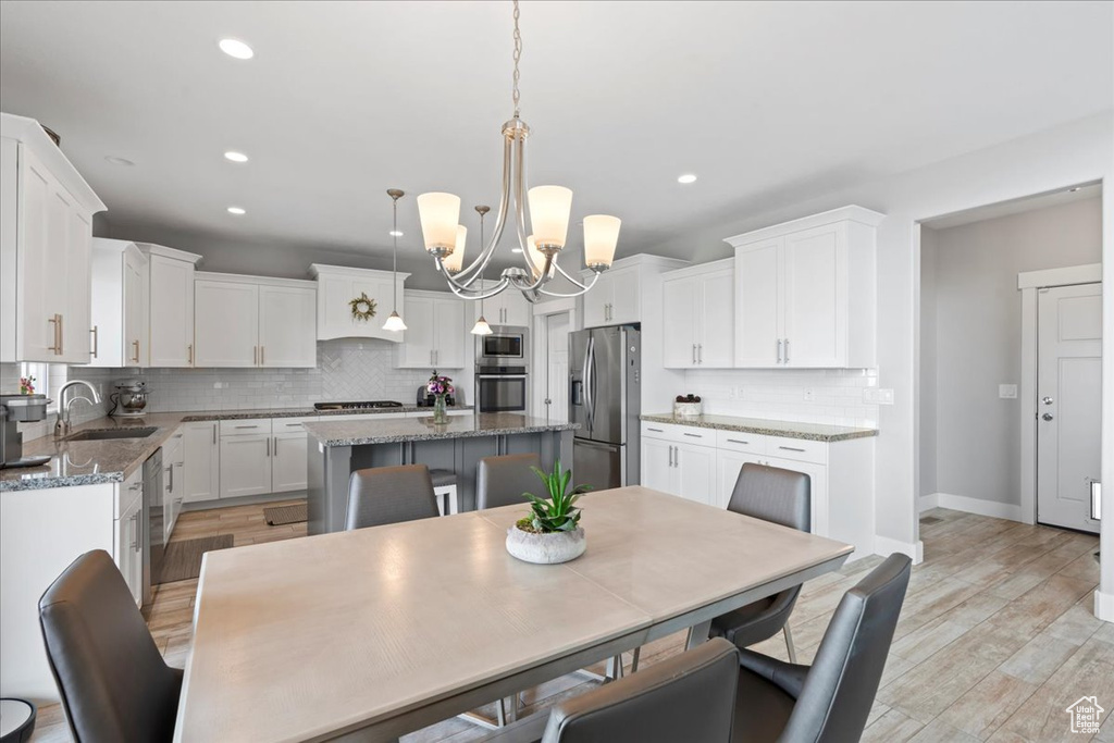 Dining area featuring a chandelier, recessed lighting, baseboards, and light wood-style flooring