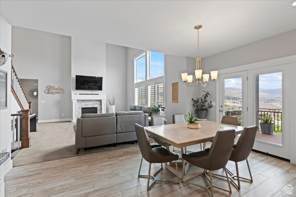 Dining area with a chandelier, light wood-style floors, a fireplace, stairs, and baseboards