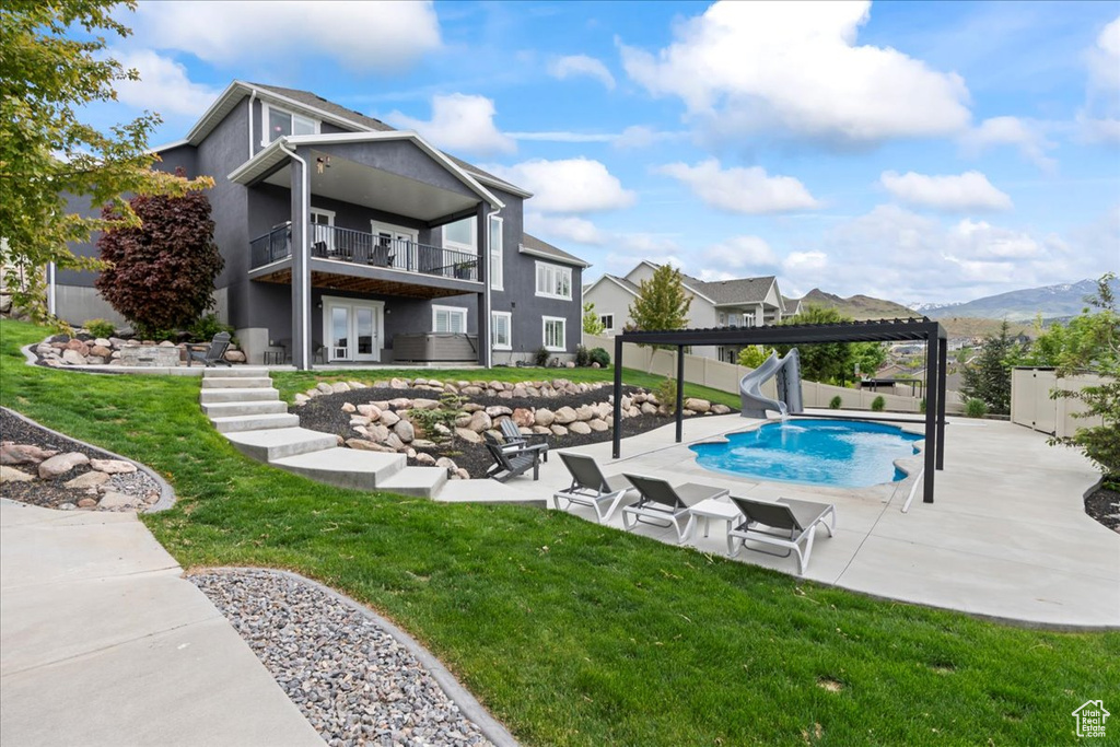 View of swimming pool with a water slide, french doors, a patio area, and a pergola