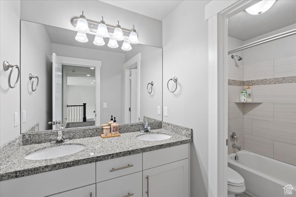 Full bath featuring double vanity, shower / bath combination, and toilet