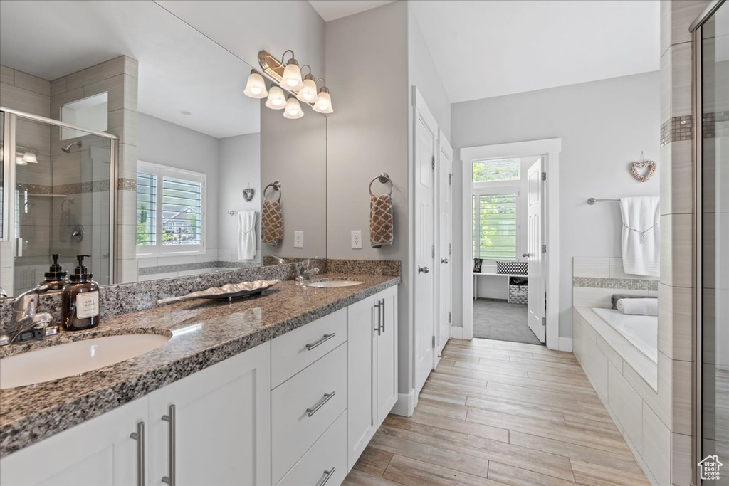 Full bath featuring plenty of natural light, a stall shower, double vanity, and a garden tub