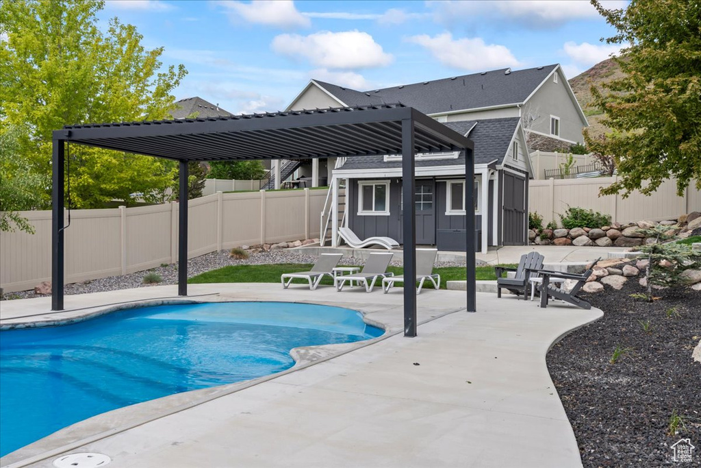 View of swimming pool featuring an outbuilding, a patio area, and a fenced backyard