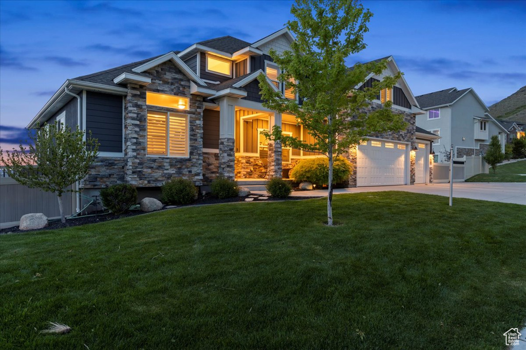 Craftsman-style home with stone siding, driveway, and a garage