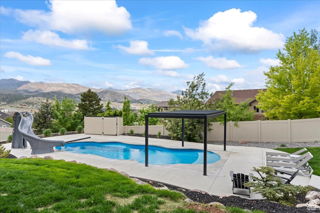 View of pool with a water slide, a patio area, and a mountain view