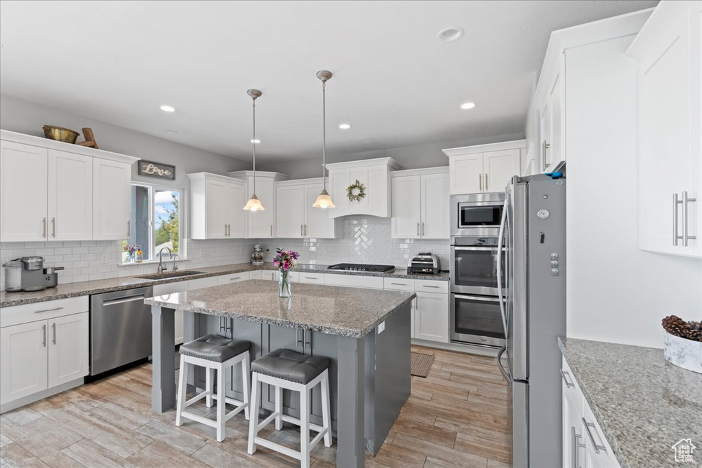 Kitchen with appliances with stainless steel finishes, a sink, white cabinetry, and recessed lighting