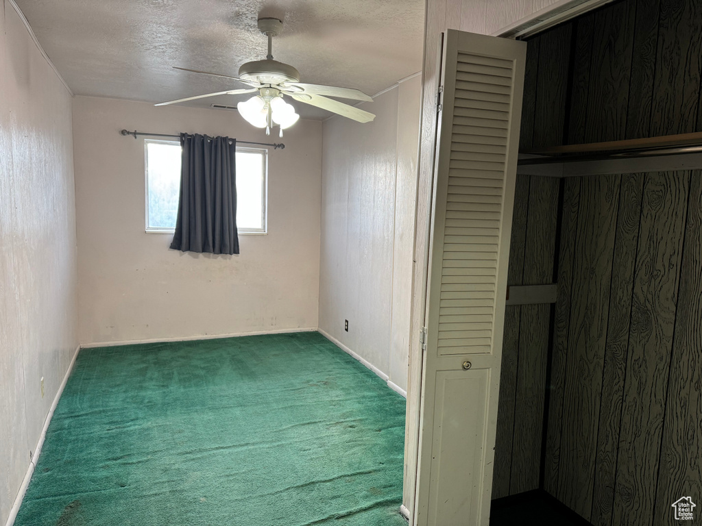 Unfurnished bedroom featuring carpet, a closet, a ceiling fan, baseboards, and a textured ceiling