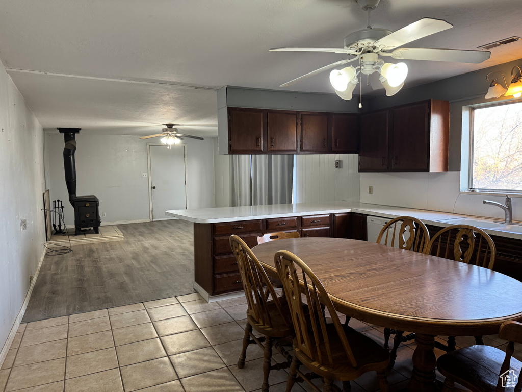 Dining area with a ceiling fan, a wood stove, light tile patterned floors, and baseboards
