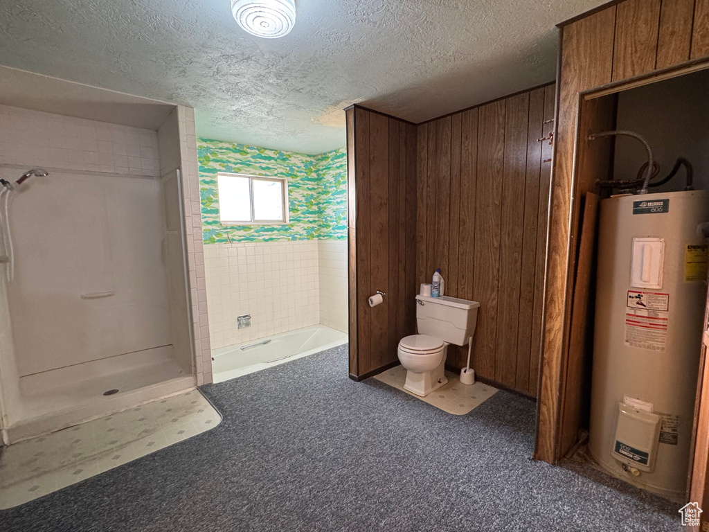 Bathroom featuring water heater, toilet, a textured ceiling, a shower, and a tub