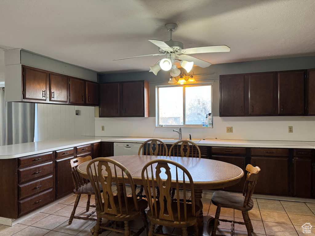 Kitchen with a ceiling fan, dark brown cabinetry, light tile patterned floors, light countertops, and a sink