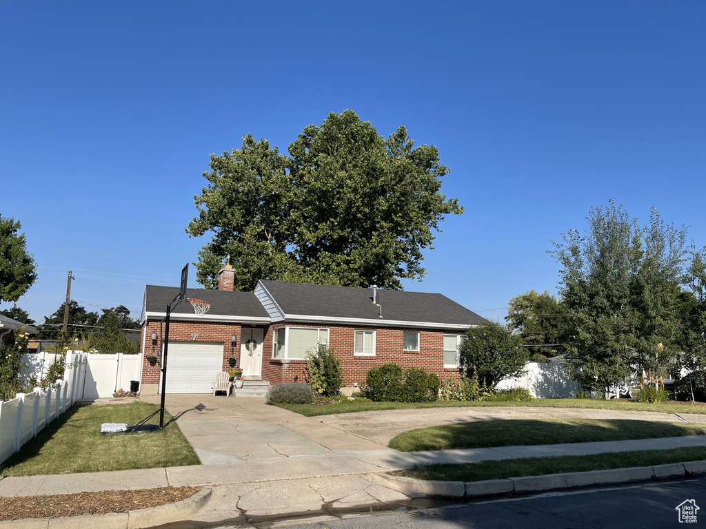 Single story home with an attached garage, brick siding, concrete driveway, and a chimney
