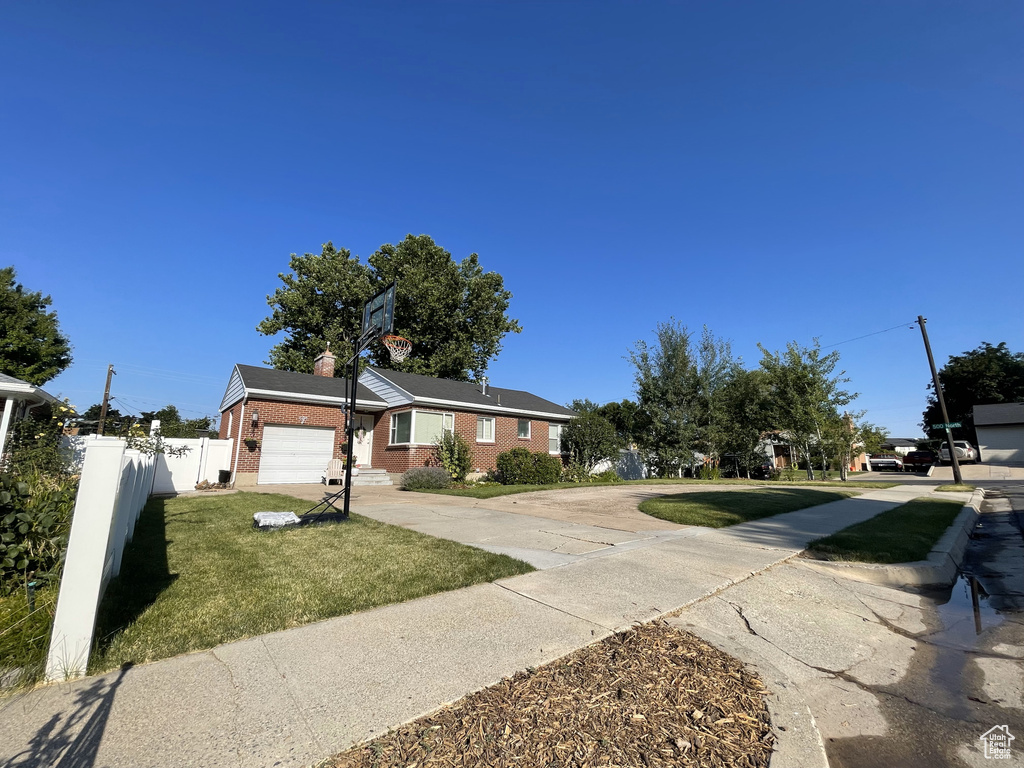 View of front of property featuring brick siding, concrete driveway, a garage, and a chimney