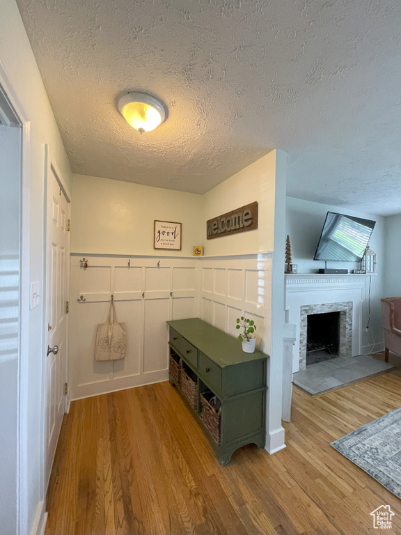 Mudroom with wood finished floors, a textured ceiling, a fireplace, and baseboards
