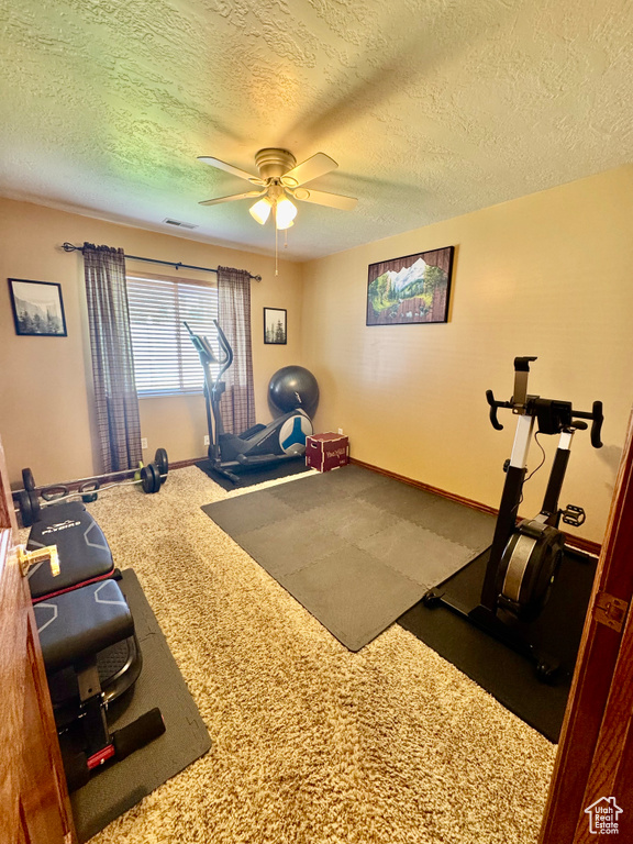 Workout room featuring a textured ceiling, a ceiling fan, and baseboards