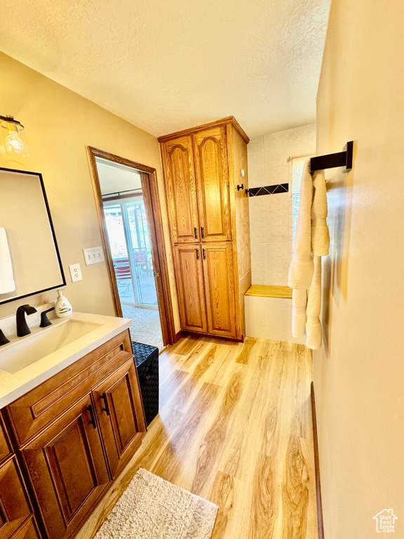 Full bath with vanity, a textured ceiling, wood finished floors, a bath, and a shower
